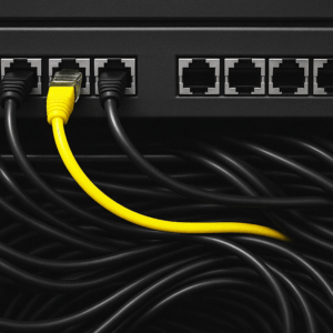 A bright yellow Ethernet cable stands out among a mass of black cables, plugged into a network switch — symbolizing differentiation, connectivity, and signal clarity in a complex system.